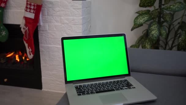 Домашняя тетрадь с рождественским фоном. Зеленый экран ноутбука. праздничное деловое время. Домашнее рабочее место у камина — стоковое видео