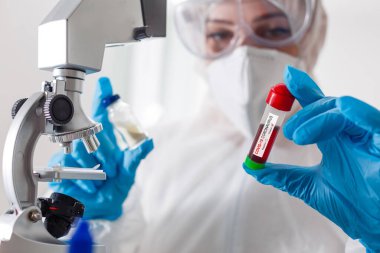 Laboratuvarda Covid-19 virüsü için mikroskoba bakan genç bir bilim adamı. Koruyucu Salgın Corona Virüsü, Covid-19 salgını konsepti