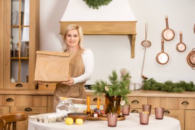 Bir paket yemek taşıyan bir kadın. Coronavirus döneminde fırın içinde yemek hazırlayan işçiler