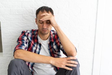 Oturma odasında düşünceli bir genç adam var.