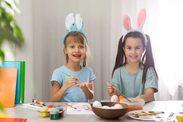 快乐的复活节 两个姐姐在画复活节彩蛋 快乐的家庭孩子为复活节做准备 复活节那天 可爱的小女孩戴着小兔子耳朵 — 图库照片