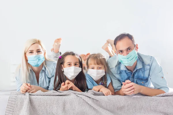 Family in medical face masks lying on a bed quarantine during a COVID-19 coronavirus epidemic
