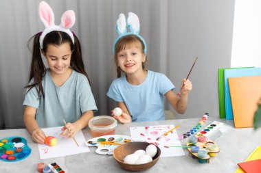 Mutlu Paskalyalar. Paskalya yumurtalarını boyayan iki kardeş. Mutlu aile çocukları Paskalya için hazırlanıyor. Paskalya günü tavşan kulağı takan şirin bir kız çocuğu..