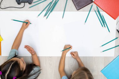 Sevimli çocuklar evde yerde yatarken resim yapıyor ve gülümsüyor.