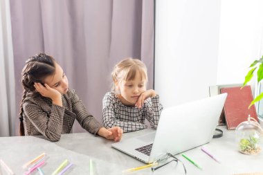 İki küçük üzgün kız internette bir dizüstü bilgisayarla çalışıyor.