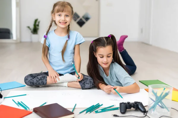 かわいい子供たちは家の床に横たわっている間に絵を描いて笑っています — ストック写真