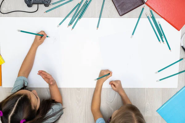 Sevimli çocuklar evde yerde yatarken resim yapıyor ve gülümsüyor.