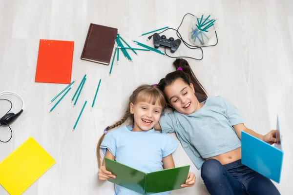 子供時代のコンセプト 幸せな姉妹が床に横たわって家で宿題をしています — ストック写真