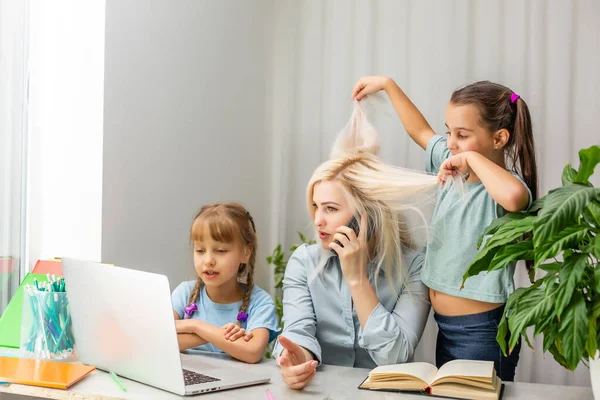 A young mother with two children works from home on a computer. Fatigue Lifestyle Housewife Freelance. tired mother and two little daughters