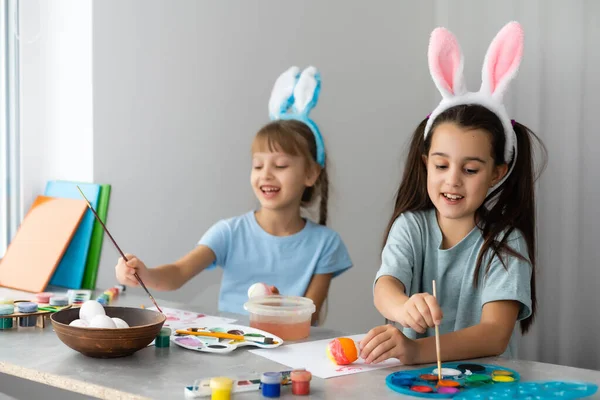 快乐的复活节 两个姐姐在画复活节彩蛋 快乐的家庭孩子为复活节做准备 复活节那天 可爱的小女孩戴着小兔子耳朵 — 图库照片