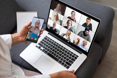Kadın çalışanın, çeşitli çok ırklı meslektaşlarıyla çevrimiçi brifingde yaptığı video konuşmasında arka planda, kadın çalışanın modern laptopta iş arkadaşlarıyla Webcam grup konferansı var.
