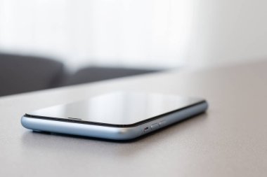 Siyah taş masa zemininde boş ekranlı modern cep telefonu. Eski koyu gri kumaş arka planında akıllı telefon.