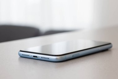 Siyah taş masa zemininde boş ekranlı modern cep telefonu. Eski koyu gri kumaş arka planında akıllı telefon.