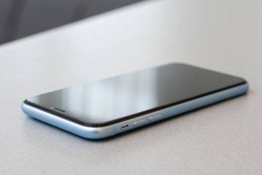 Siyah taş masa zemininde boş ekranlı modern cep telefonu. Eski koyu gri kumaş arka planında akıllı telefon.