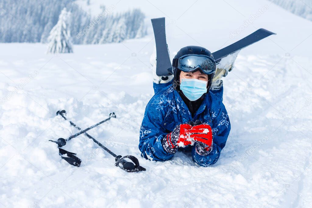 Portrait of a woman skier in medical mask during COVID-19 coronavirus on a snowy mountain at a ski resort