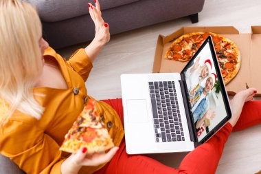 Noel 'de ailesi ve arkadaşlarıyla bilgisayar kullanarak görüntülü konuşma yapan beyaz bir kadın. Noel zamanı covid 19 salgınında sosyal mesafeler.