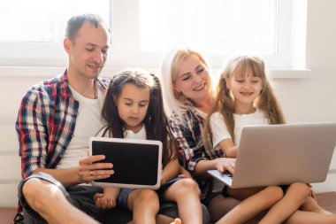 Mutlu aile kavramı. Güzel anne ve yakışıklı baba ve kızları evde birlikte vakit geçiriyorlar ve dizüstü bilgisayarla yatakta yatıyorlar..
