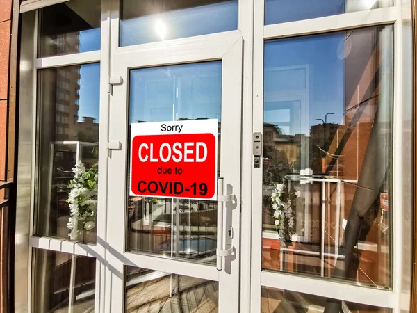 Business center closed due to COVID-19, sign with sorry in door window. Stores, restaurants, offices, other public places temporarily closed during coronavirus pandemic. Economy hit by corona virus.