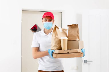 Temassız pizza teslimatı. Pizza kutusu. Karton kutuları tıbbi lastik eldiven ve maskeyle taşıyan teslimatçı. Hızlı ve ücretsiz teslimat. İnternetten alışveriş ve ekspres teslimat. Karantina