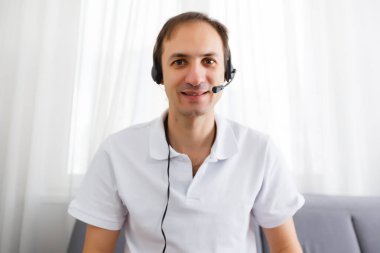 Bilgisayarda kulaklıklarla video görüşmesi yapan mutlu olgun bir adamın portresi. Neşeli gündelik iş adamı evde video görüşmesi yapıyor..