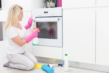 Genç bir kadın ev işi yapıyor, mutfağı temizliyor.