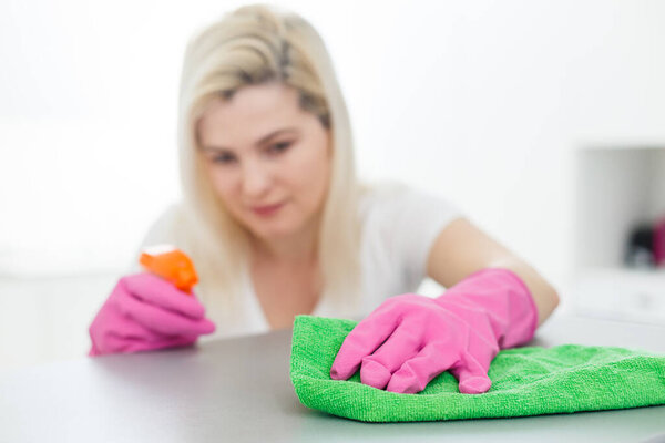 Woman cleaning dust from bookshelf. Young girl sweeping shelf, spring cleaning concept, copy space