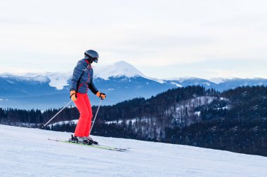 Kışın Coronavirus. Yüz maskesiyle kayak yapmak. Pandemia 'da kış tatili. Yüz maskeli beyaz bir gencin portresi. Kış yeni bir gerçeklikle geliyor..