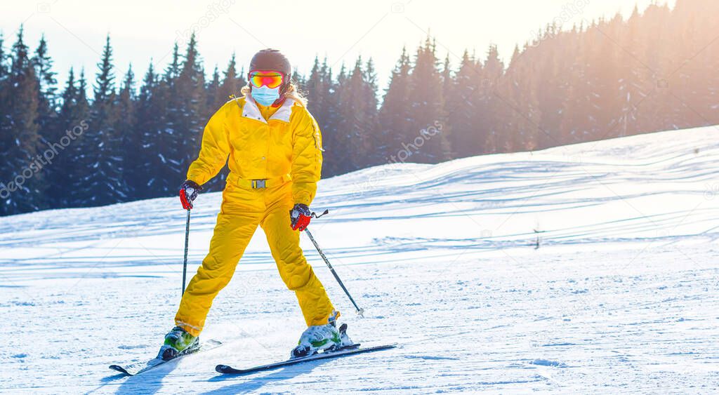 Woman wearing a medical mask during COVID-19 coronavirus on a sunny winter day at a ski resort