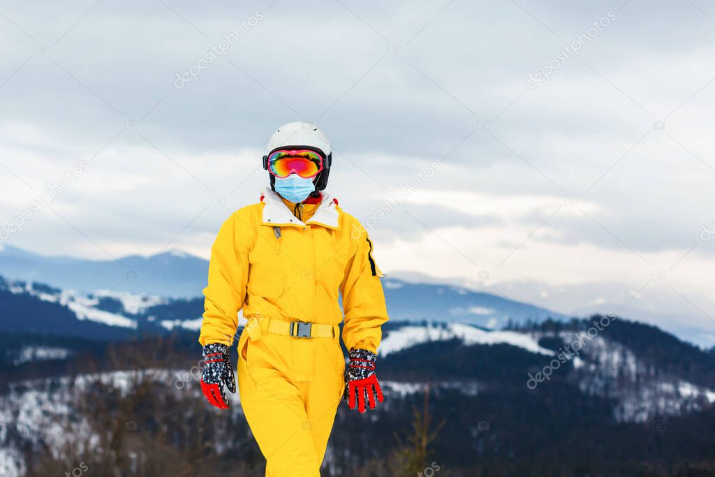 Woman wearing a medical mask during COVID-19 coronavirus on a sunny winter day at a ski resort