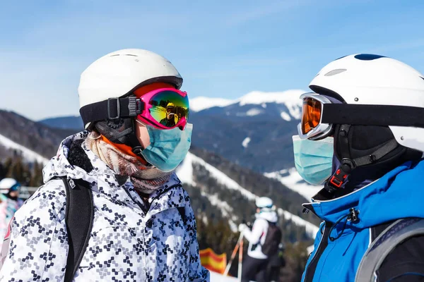 Skidåkare med medicinsk mask under COVID-19 coronavirus i skidorten. Man och kvinna tillsammans i vinternaturen. Romantiskt landskap. Sportfoto — Stockfoto