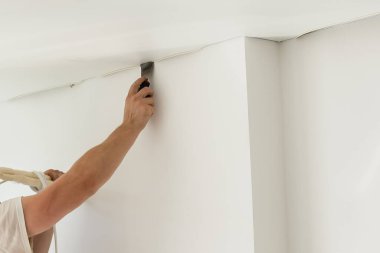 Koridora esnek tavan kurma işlemi. Bir aletle insanın elini kapat..