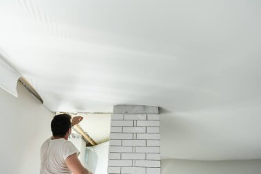 Koridora esnek tavan kurma işlemi. Bir aletle insanın elini kapat..