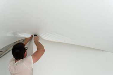 Tamirciler PVC vinil filmden yapılmış esnek tavanı gaz tabancasıyla kuruyorlar.