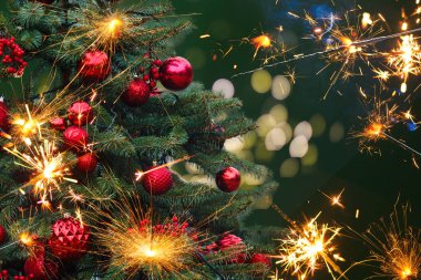 Arka planda Noel ışığı saçan bir maytap.