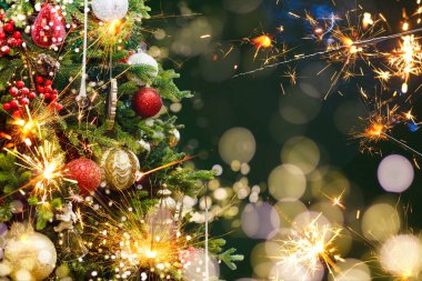 Arka planda Noel ışığı saçan bir maytap.