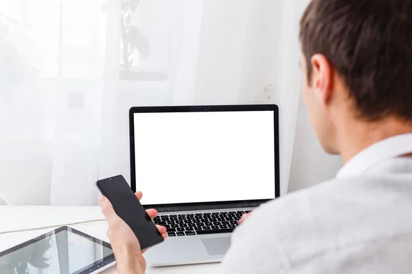 Back view of male person sitting front open laptop computer with blank empty screen for your information or content, modern businessman working in internet