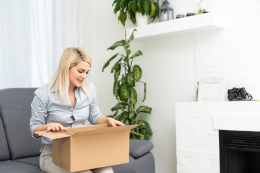 Ulaşım, posta ve insan konsepti - gülümseyen genç kadın evde karton kutu açıyor