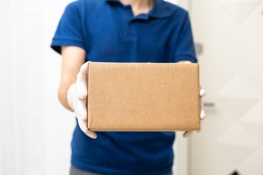 Karton kutuları tıbbi lastik eldiven ve maskeyle taşıyan teslimatçı. kopyalama alanı. Hızlı ve ücretsiz teslimat. İnternetten alışveriş ve ekspres teslimat. Karantina
