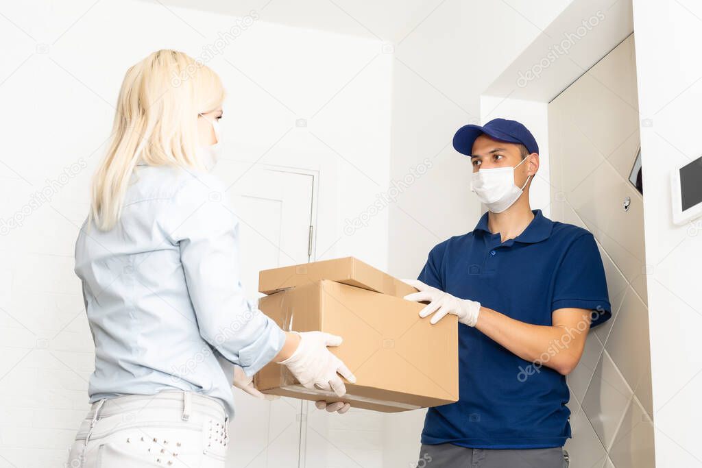 A courier in a protective mask and a glove delivers food to a woman. Volunteer delivers fresh food to those in need