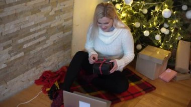 Young woman at home in Christmas time talking on video chat online on laptop computer. Happy and smiling, christmas tree in background.