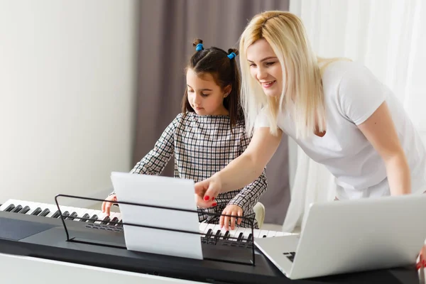 Jolie petite fille joue au piano, synthétiseur. Entraînement. L'éducation. L'école. Un entraînement esthétique. Classe élémentaire. — Photo