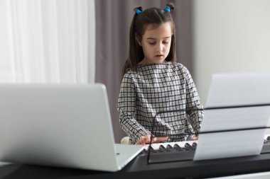 Piyano çalan kız için ev müziği dersi. Karantina sırasında çocuk için evde aktivite fikri. Müzik konsepti