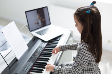 Piyano çalan kız için ev müziği dersi. Karantina sırasında çocuk için evde aktivite fikri. Müzik konsepti
