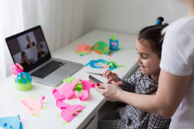 Çocukla evde çalışmak. Mutlu kız kucaklayan anne. Laptop kullanan genç bir kadın ve sevimli bir çocuk. Serbest çalışan işyeri. Kadın işi, uzaktan öğrenme. Yaşam tarzı aile anı.