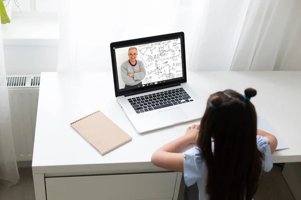 Colegiala bastante elegante que estudia matemáticas de la tarea durante su lección en línea en el hogar, distancia social durante la cuarentena, auto-aislamiento, concepto de educación en línea, colegiala en casa — Foto de Stock