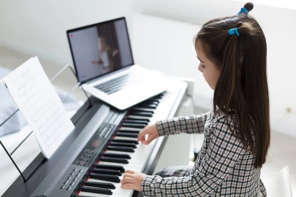 Home lesson on music for the girl on the piano. The idea of activities for the child at home during quarantine. Music concept