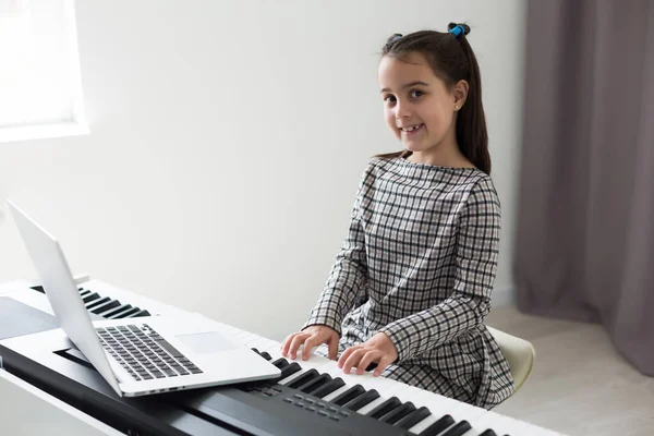 Home lesson on music for the girl on the piano. The idea of activities for the child at home during quarantine. Music concept