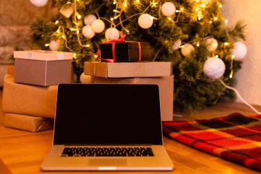 Boş beyaz ekranlı dizüstü bilgisayar hediyeler, Noel Baba evinin arka planında süslenmiş Noel ağacı. Etrade web sitesi online alışveriş dağıtım reklamları.