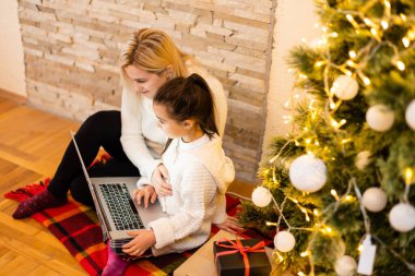 Anne ve kız, covid-19 karantina, sosyal uzaklık, kendini izole etme süresince dizüstü bilgisayardaki akrabalarıyla çevrimiçi iletişim kuruyor. Çocuklar Noel tatili boyunca evde kalıyordu. ..