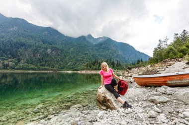 Kaygısız kadın turist gölün yakınındaki ormanda dinleniyor.